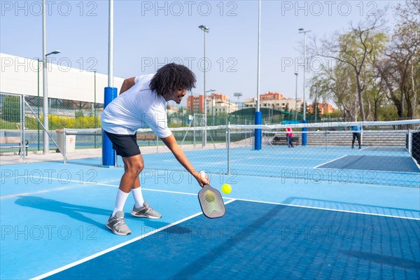 Full length photo of two african american young male friends playing pickleball together in an outdoor court