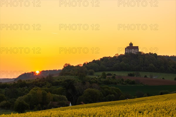 Landscape at sunrise. Beautiful morning landscape with fresh yellow rape fields in spring. Small castle in the yellow fields on a hill. Historic Ronneburg Castle in the middle of nature, Ronneburg, Hesse, Germany, Europe