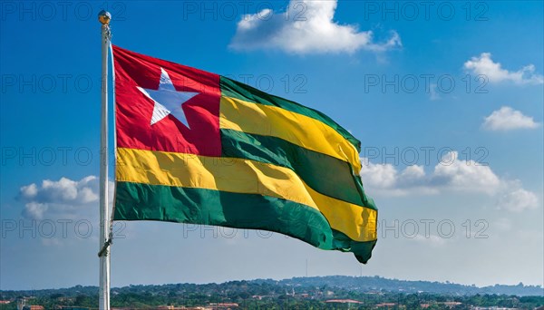 The flag of Togo flutters in the wind, isolated against a blue sky