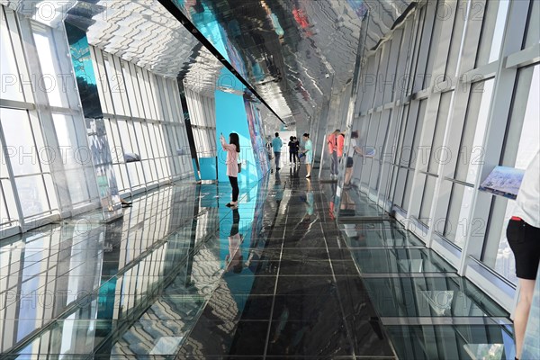 Viewing terrace, The Bottle Opener at 492 metres, people walk along a glass viewing corridor with reflections on the wall and ceiling, Shanghai, China, Asia