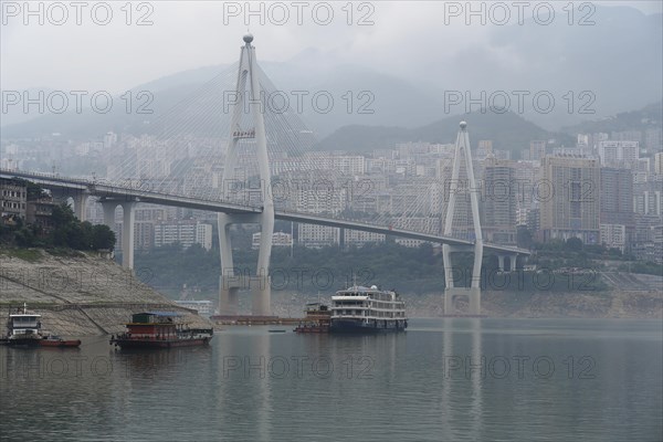 Chongqing, Chongqing Province, Modern bridge over a river with light fog, cityscape behind, Chongqing, Chongqing Province, China, Asia