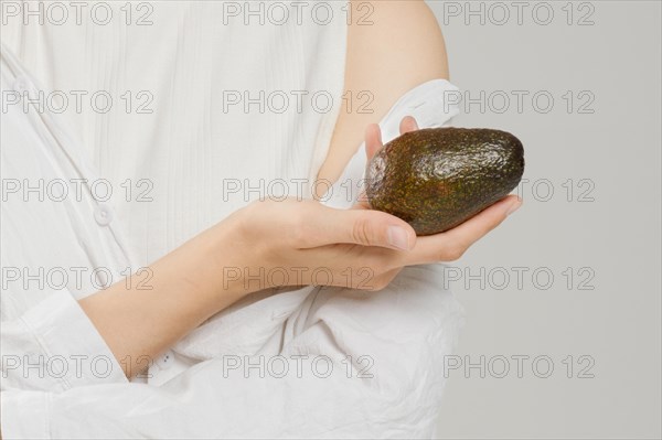 Unrecognizable woman holds avocado in hand