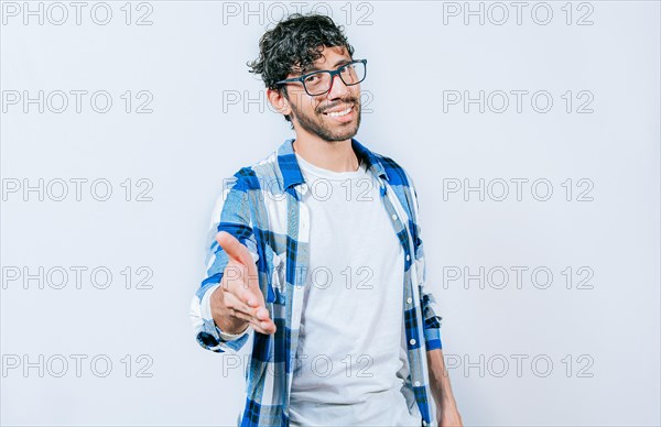 Smiling young man shaking his hand at the camera. Guy in glasses shaking hands at camera isolated