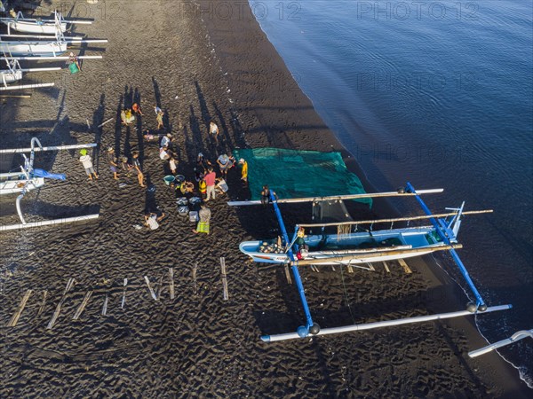 Fishermen unload their catch from their outrigger boat in the morning. Amed, Karangasem, Bali, Indonesia, Asia