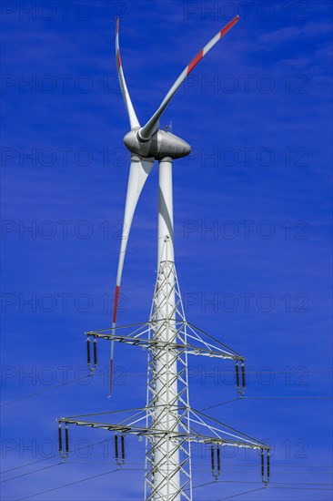 Electricity pylon with high-voltage lines and wind turbine at the Avacon substation Helmstedt, Helmstedt, Lower Saxony, Germany, Europe