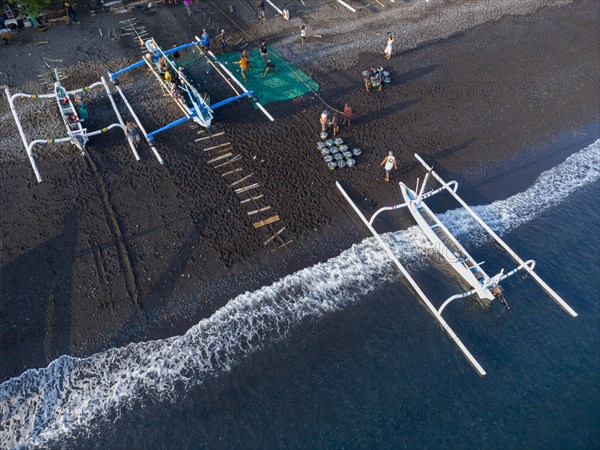 Fishermen unload their catch from their outrigger boat in the morning. Amed, Karangasem, Bali, Indonesia, Asia