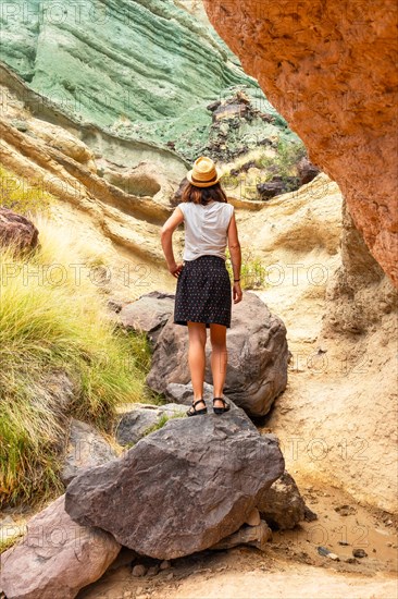 A tourist woman with a hat at the Azulejos de Veneguera or Rainbow Rocks in Mogan, Gran Canaria