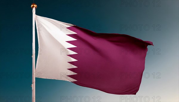 The flag of Qatar flutters in the wind, isolated against a blue sky