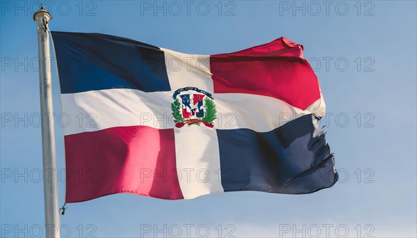 The flag of the Dominican Republic flutters in the wind, isolated against a blue sky