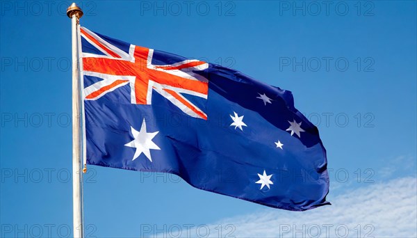 The flag of Australia flutters in the wind, isolated against a blue sky