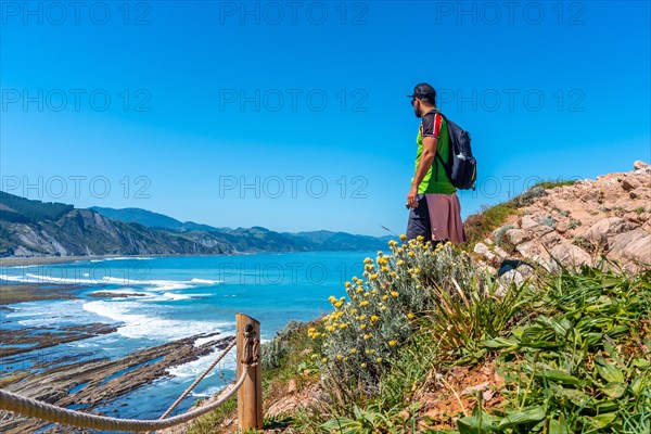 A male hiker in Algorri cove on the coast in the flysch of Zumaia, Gipuzkoa. Basque Country