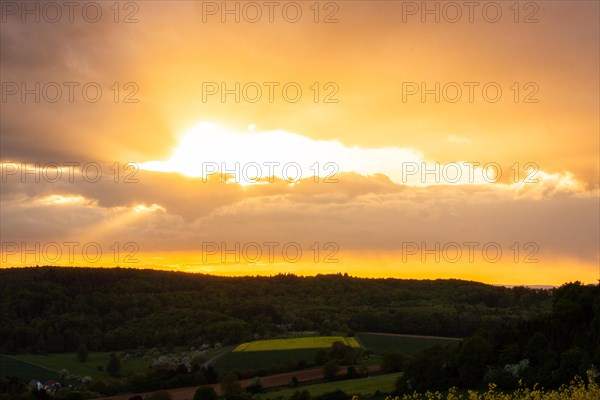 Landscape at sunrise. Beautiful morning landscape with fresh yellow rape fields in spring. Small castle in the yellow fields on a hill. Historic Ronneburg Castle in the middle of nature, Ronneburg, Hesse, Germany, Europe