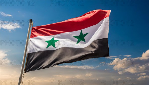 The flag of Syria flutters in the wind, isolated against a blue sky