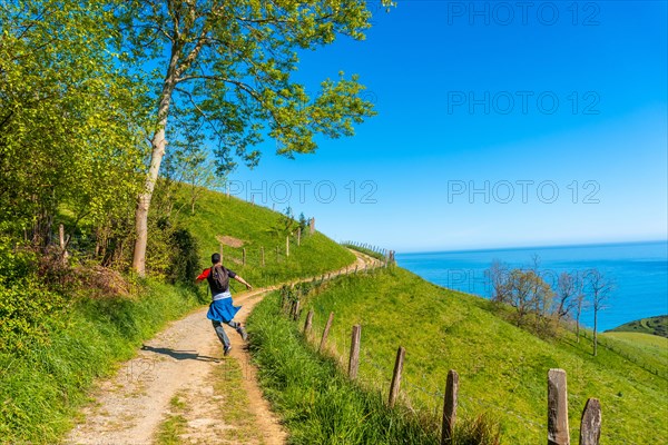 A very happy man jumping while trekking on the climb to the flysch of Zumaia, Gipuzkoa. Basque Country