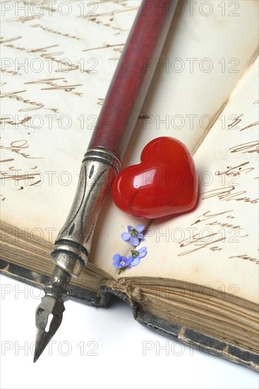 Pen with pen holder and red heart on diary