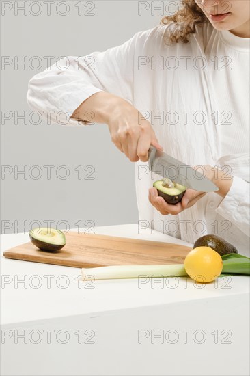 Unrecognizable woman removes a pit from an avocado using a knife