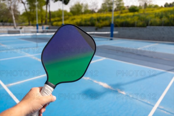 Close-up of a hand holding pickleball racket in an outdoor court