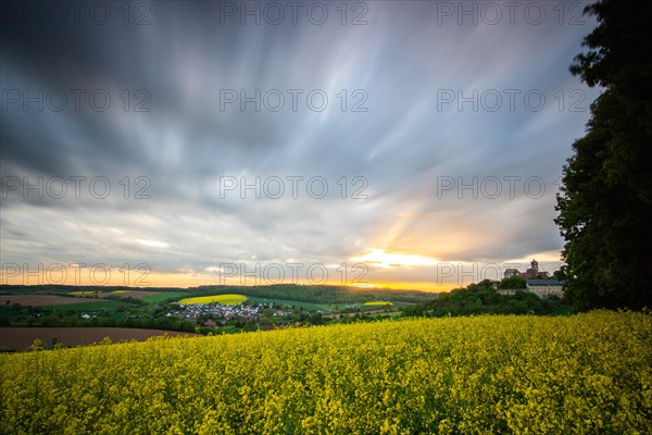 Landscape at sunrise. Beautiful morning landscape with fresh yellow rape fields in spring. Small castle in the yellow fields on a hill. Historic Ronneburg Castle in the middle of nature, Ronneburg, Hesse, Germany, Europe