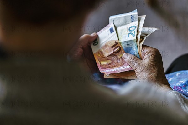 Senior citizen with wrinkled hands counts her money at home in her flat and holds banknotes in her hand, Cologne, North Rhine-Westphalia, Germany, Europe