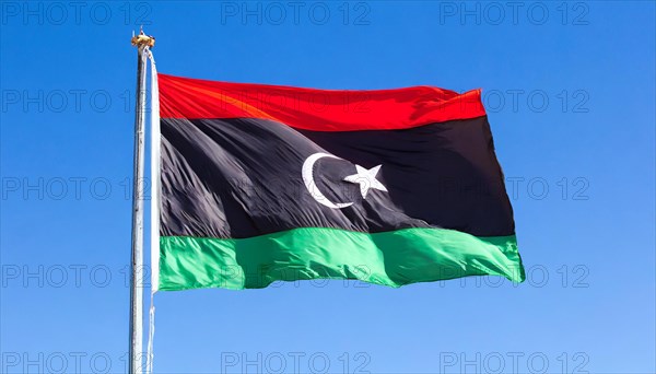 The flag of Libya, fluttering in the wind, isolated, against the blue sky