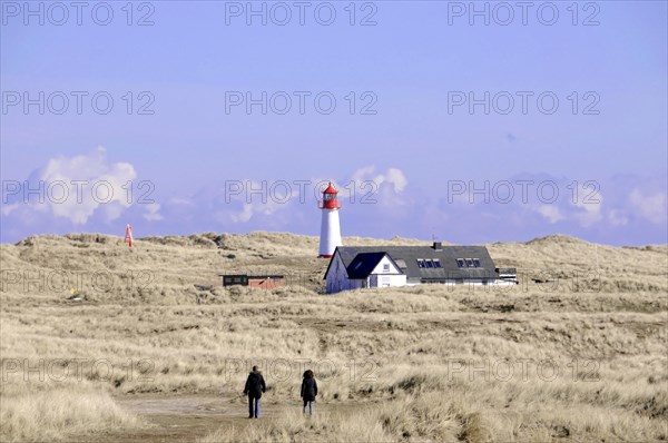 Sylt, Schleswig-Holstein, Two people walking towards a lighthouse with neighbouring houses on the coast, Sylt, North Frisian Island, Schleswig-Holstein, Germany, Europe