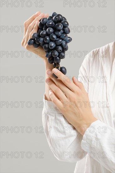 Unrecognizable woman holds a bunch of ripe grapes in her hand