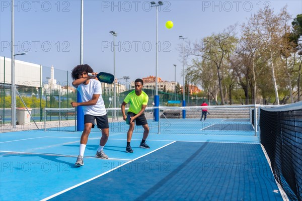 Full length photo with copy space of two african sportive friends playing pickleball together outdoors