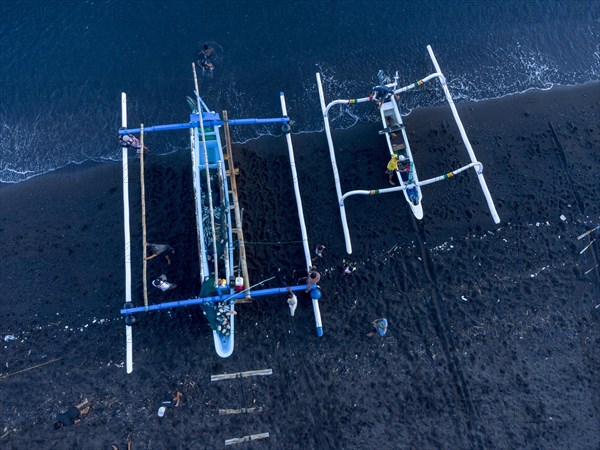 Fishermen unload their catch from their outrigger boat in the morning. Amed, Karangasem, Bali, Indonesia, Asia