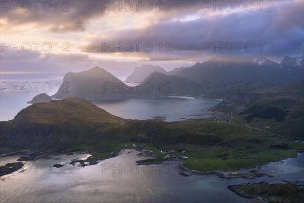 Landscape on the Lofoten Islands. View from the mountain Offersoykammen to the sea, the mountains Veggen, Mannen, Himmeltindan and Hogskolmen as well as the beaches of Haukland (Hauklandstranda) and Vik (Vik Beach) . At night at the time of the midnight sun. Clouds in the sky, sunlight from the side. Vestvagoya, Lofoten, Norway, Europe