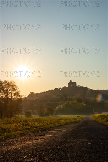 Landscape at sunrise. Beautiful morning landscape with fresh yellow rape fields in spring. Small castle in the yellow fields on a hill. Historic Ronneburg Castle in the middle of nature, Ronneburg, Hesse, Germany, Europe