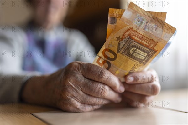 Senior citizen with wrinkled hands counts her money at home in her flat and holds banknotes in her hand, Cologne, North Rhine-Westphalia, Germany, Europe