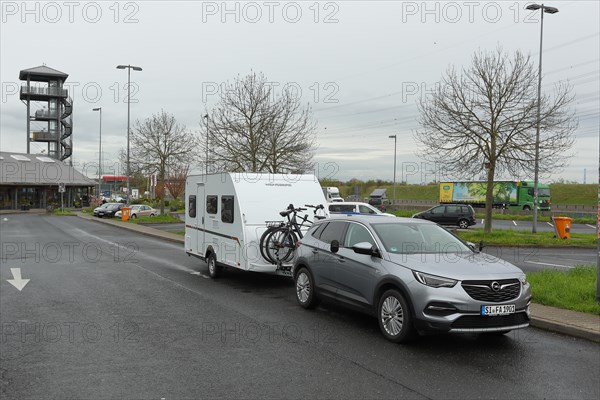 Car with caravan parked on a motorway service area, Tank und Rast, Wetterau Ost service area, Hesse, Germany, Europe