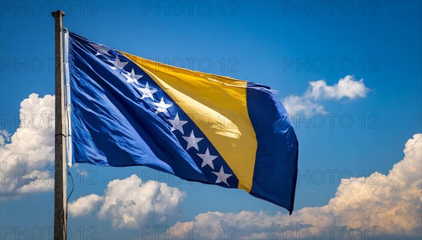 The flag of Bosnia and Herzegovina flutters in the wind, isolated against a blue sky