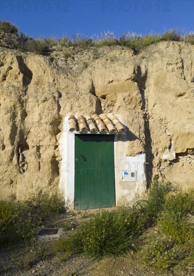 A green door built into a rock face under a clear blue sky, cave dwelling, Valtierra, Navarra, Spain, Europe