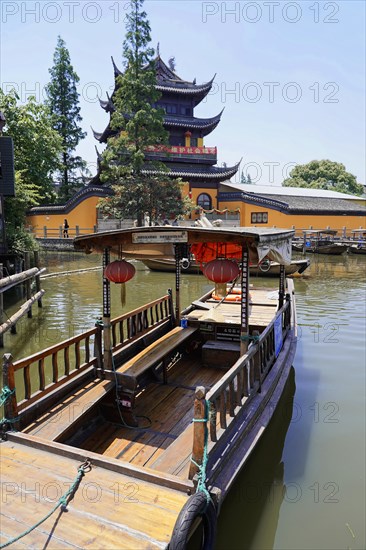 Excursion to Zhujiajiao water village, Shanghai, China, Asia, Wooden boat on canal with view of historical architecture, Traditional temple on the water with a boat in the foreground under a clear blue sky, Asia