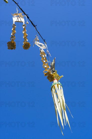 Ornate jewellery woven from palm leaves on bamboo poles, on a village street in Amed, Karangasem, north-east Bali, Indonesia, Asia