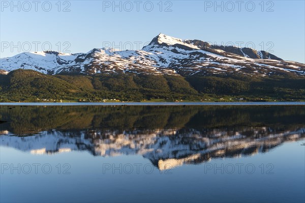 Landscape in Norway. The Balsfjord with a view of Mount Fugltinden. At night during the midnight sun, good weather, blue sky. Early summer. Reflection. Balsfjord, Norway, Europe