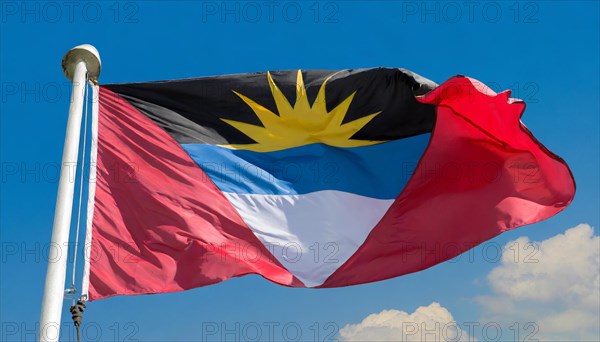 The flag of Antigua flutters in the wind, isolated against the blue sky