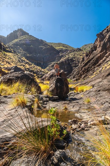 A hiker on the river on the climb to Charco Azul in the Podemos to Agaete in Gran Canaria, Canary Islands