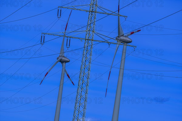 Wind energy in an inclined position, theme photo, electricity pylon with high-voltage lines and wind turbines at the Avacon substation in Helmstedt, Helmstedt, Lower Saxony, Germany, Europe