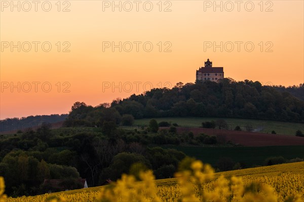 Landscape at sunrise. Beautiful morning landscape with fresh yellow rape fields in spring. Small castle in the yellow fields on a hill. Historic Ronneburg Castle in the middle of nature, Ronneburg, Hesse, Germany, Europe