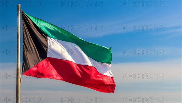 The flag of Kuwait flutters in the wind, isolated against a blue sky