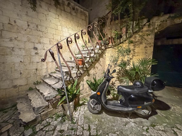 An old staircase with an abandoned scooter in a nocturnal setting, Trogir, Dalmatia, Croatia, Europe