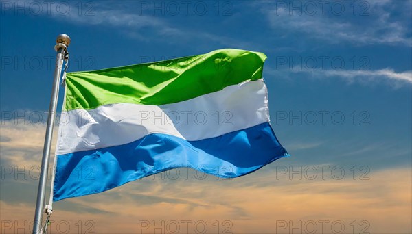 The flag of Sierra Leone, fluttering in the wind, isolated, against the blue sky