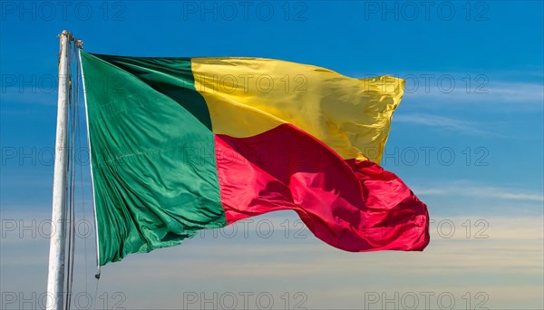 The flag of Benin flutters in the wind, isolated against the blue sky