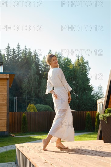 Barefoot woman dancing on terrace of log cabin