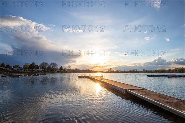 View from the shore into the distance and a sunset on the lake. The surroundings and the marvellous sky are reflected in the water. A great landscape shot Dutenhofener See, Hesse Germany