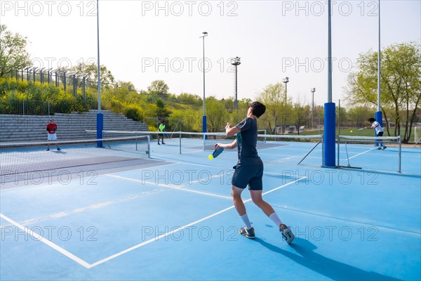 Full length of men playing pickleball in an outdoor court