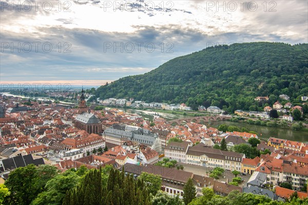 View over an old town with churches in the evening at sunset. This town lies in a river valley of the Neckar, surrounded by hills. Heidelberg, Baden-Wuerttemberg, Germany, Europe