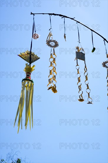 Ornate jewellery woven from palm leaves on bamboo poles, on a village street in Amed, Karangasem, north-east Bali, Indonesia, Asia